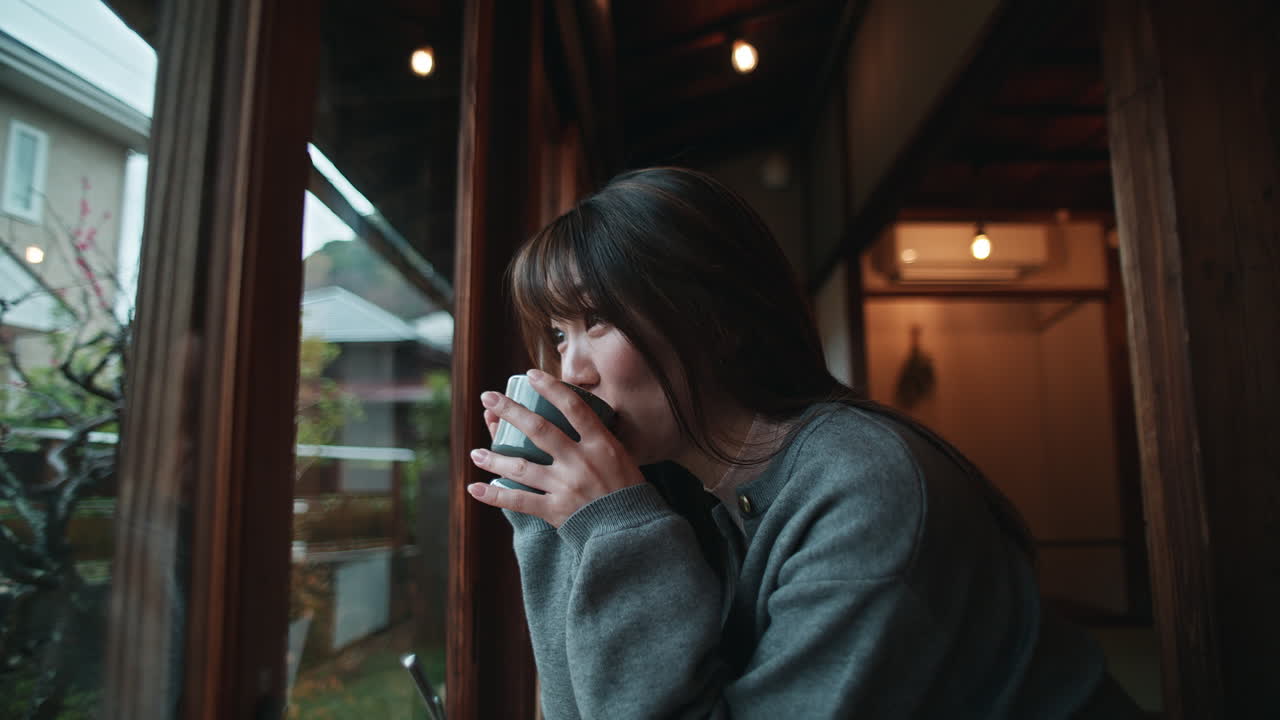 A woman is having a cup of coffee indoor