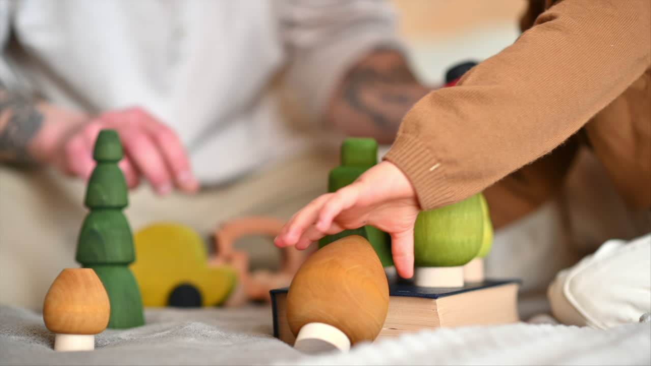 Father playing with his son with colourful, ecological wooden toys on the bed