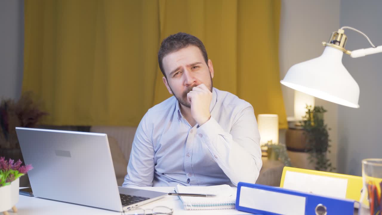 Home office worker man biting his nails looking at camera.