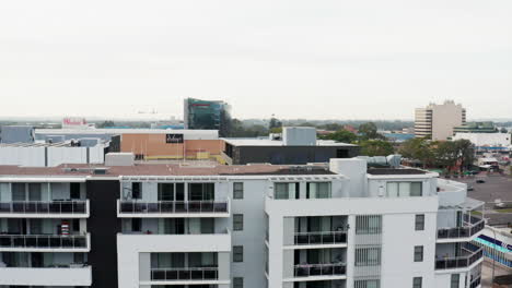 Toma-Aérea-De-Un-Dron-Que-Asciende-Sobre-Un-Complejo-De-Apartamentos-Para-Revelar-El-Centro-De-La-Ciudad-De-Liverpool,-Sydney,-Australia.