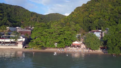 Smooth-aerial-top-view-flight-Beach-Village-Huts-Resort,-tropical-Bungalows-on-Mountainous-Island-Thailand-2022