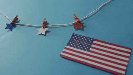 American-flag-with-red-and-blue-stars-hanging-on-line-on-blue-background