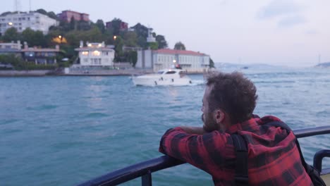 Thoughtful-man-watching-yacht-transit-on-ferry.