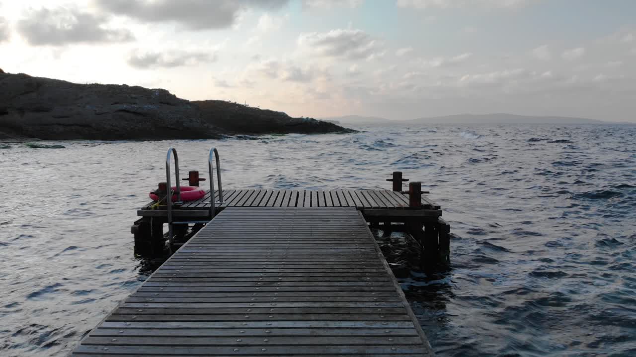 la toma se mueve horizontalmente a lo largo del muelle de madera desde la orilla hasta el mar al atardecer, bulgaria