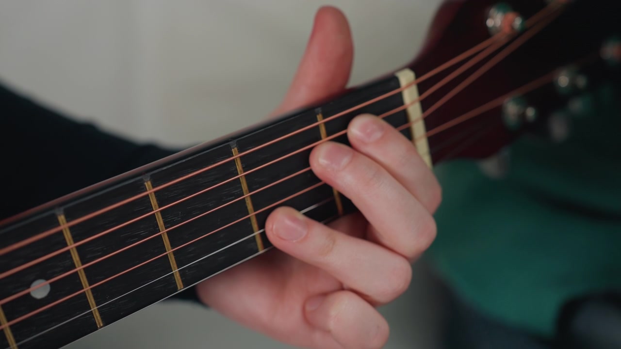 Closeup acoustic guitar fretting in apartment young person practicing fingerstyle on new couch, warm natural light, focus on left hand on fretboard, subtle movement, intimate practice mood, unpacked
