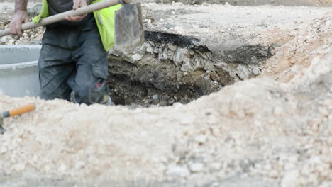 construction worker digs up beside the concrete pipe at roadwork in leiria, portugal