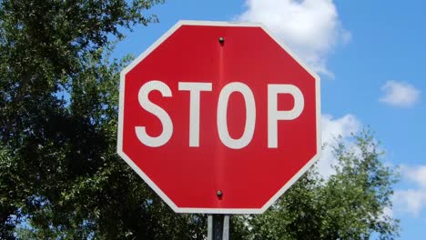 red and white stop sign with billowing clouds in the background