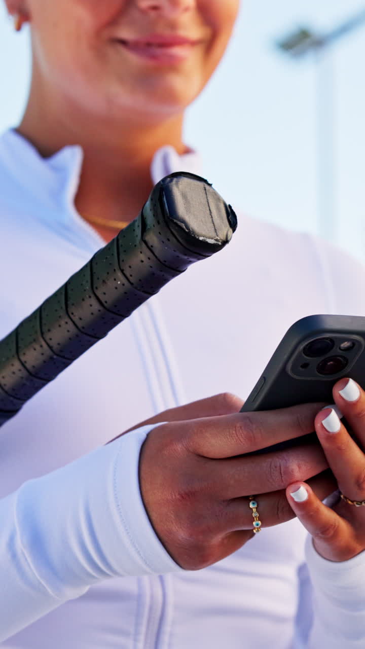 Donna che tiene una racchetta da tennis e usa lo smartphone all'aperto.