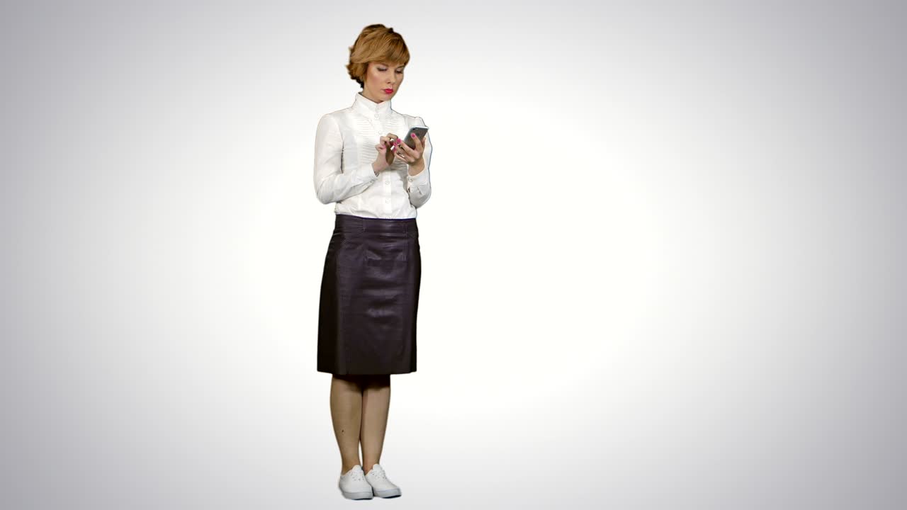 젊은 예쁜 금발 여성이  바탕에 스마트폰으로 타이핑을 하고 있습니다.