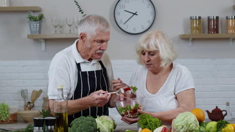 senior woman and man feeding each other with fresh raw vegetable salad. eco food eating diet