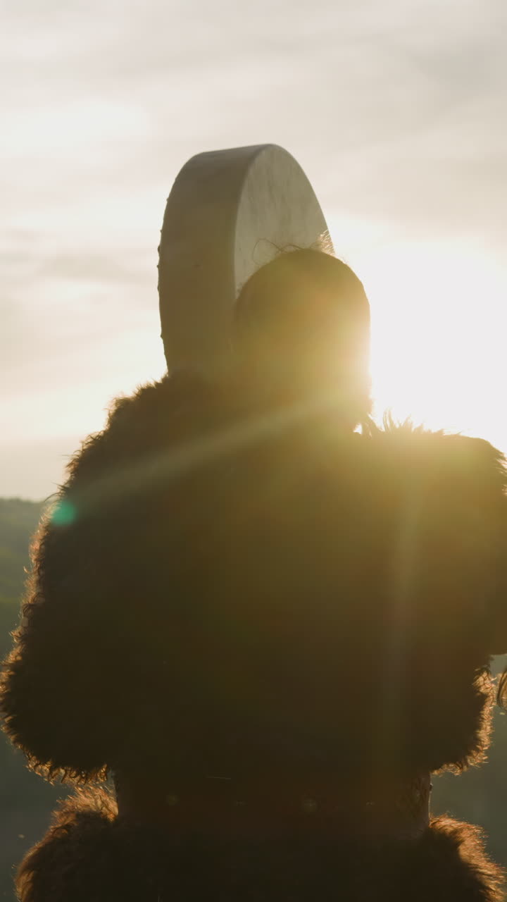 Silhouette of man conducting battle victory ceremony with shaman drum against mountains backside view. Siberian land mystical rituals. Altai culture