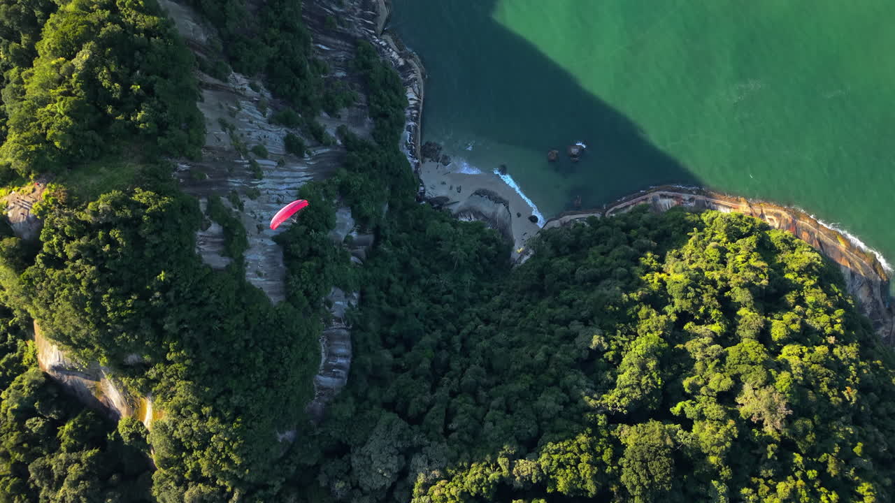 Aerial tops down paragliding fly in tropical hill seaside, beach at Caiobá, Matinhos, Paraná, Brasil. Morro do Boi,