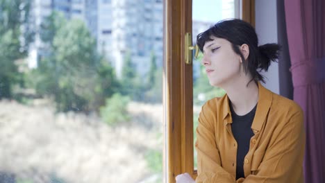 emotional young woman watching outside the window.