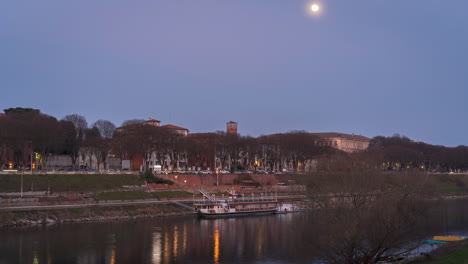 Der-Fluss-Tessin-Fließt-In-Der-Nähe-Des-Zentrums-Der-Stadt-Pavia,-Im-Hintergrund-Stadtverkehr-Und-Bewegung-Des-Mondes-Am-Himmel,-Zeitraffer-30-Fps