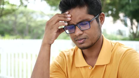 Young-man-suffering-headache-sitting-outdoor
