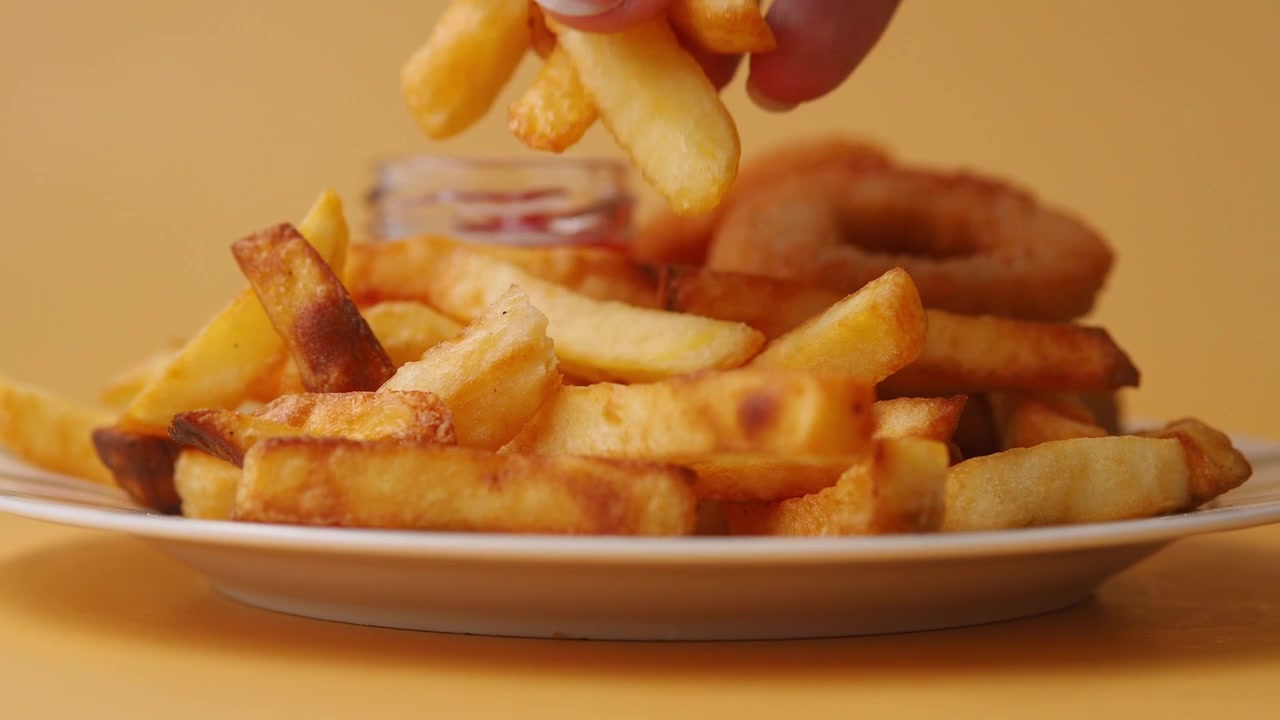 Hand Picking a French Fry from a Plate