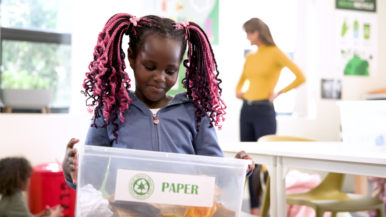 Holding recycling bin in school, African American child promoting eco-friendly habits