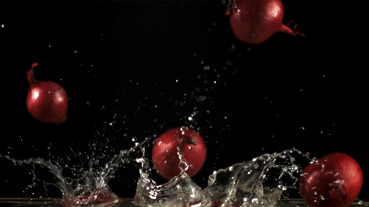 Red Onions Falling and Splashing into Water in Slow Motion