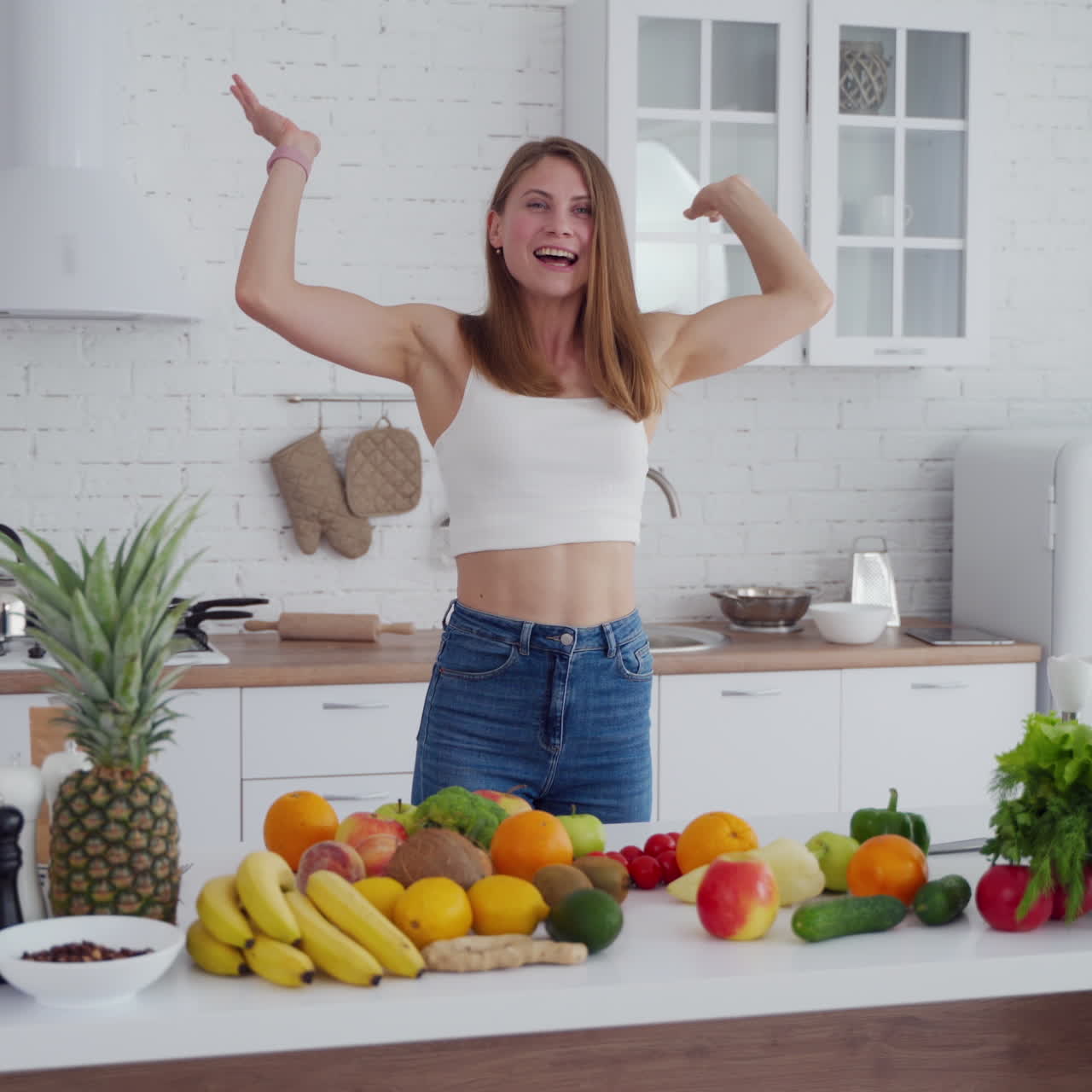 Happy young female in the kitchen. Beautiful lady throws away centimeter and takes banana. Fresh fruit and vegetables on the table. Healthy diet.
