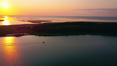 Sunset-at-the-sea,-an-island-in-the-background,-calm-water,-perfect-evening,-boat-driving-across-the-bay