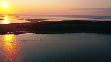 sunset at the sea, an island in the background, calm water, perfect evening, boat driving across the bay