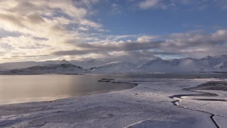 an awe-inspiring aerial perspective reveals a majestic expanse of snow-capped mountains, their rugged peaks piercing a vast, often cloud-streaked sky. iceland.