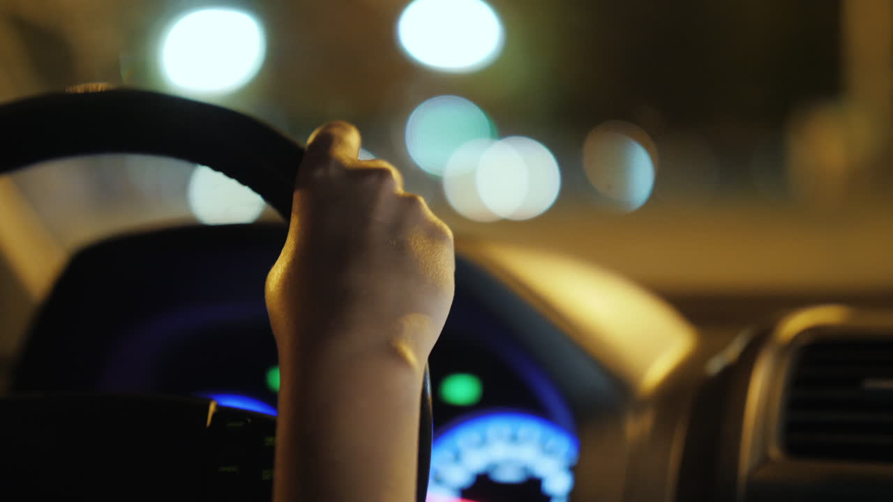 안경을 쓴 여성이 야간 도시 4k 비디오를 통해 차를 운전합니다.