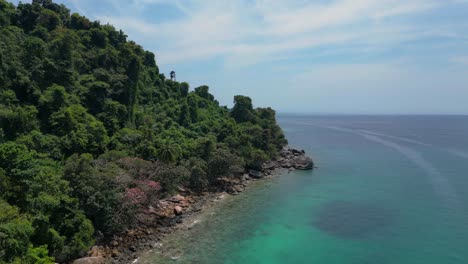 Island-Hill-Huts-in-lush-Jungle-fores,-emerald-waters-lagoon