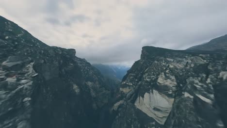las vistas aéreas muestran una cámara deslizándose sobre las cordilleras de las montañas, revelando un valle profundo y impresionante debajo.