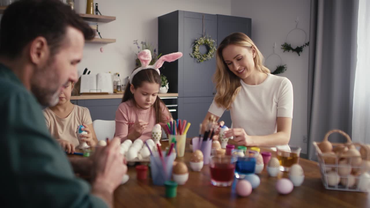 Cheerful caucasian family of four people decorating easter eggs at home.