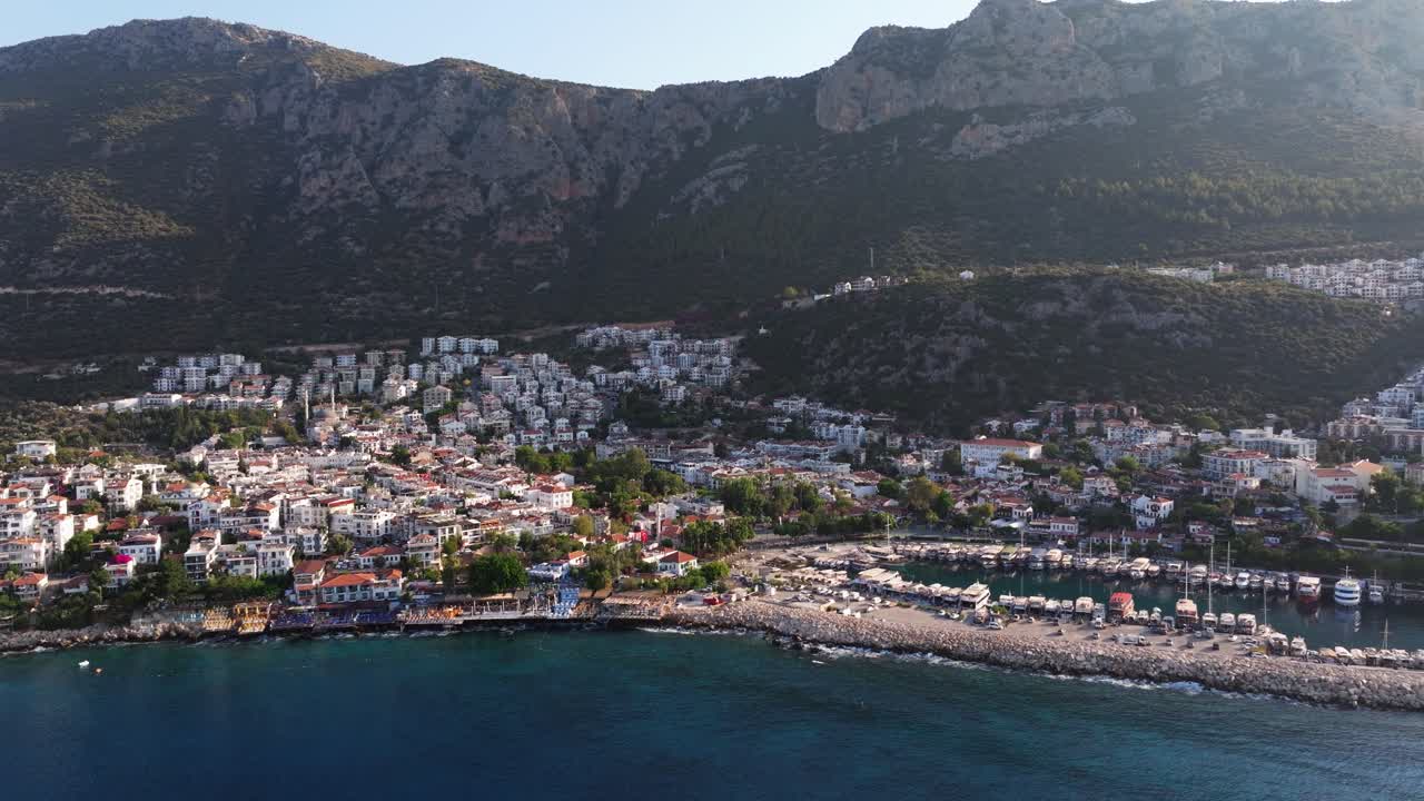 Aerial trucking pan of Kas, Antalya, Turkey, with boats docked in the marina and the sprawling coastline along the Mediterranean Sea