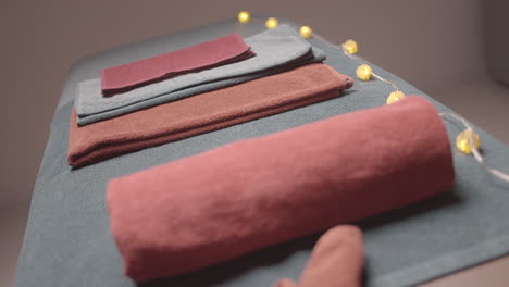 stacked towels on massage table with string lights