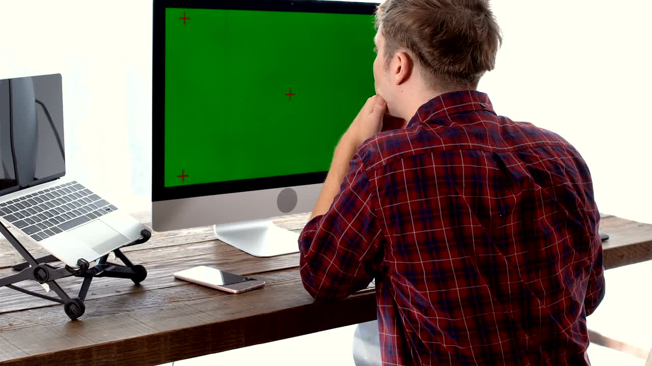 joven trabajador independiente en la mesa y trabajando con pantalla verde