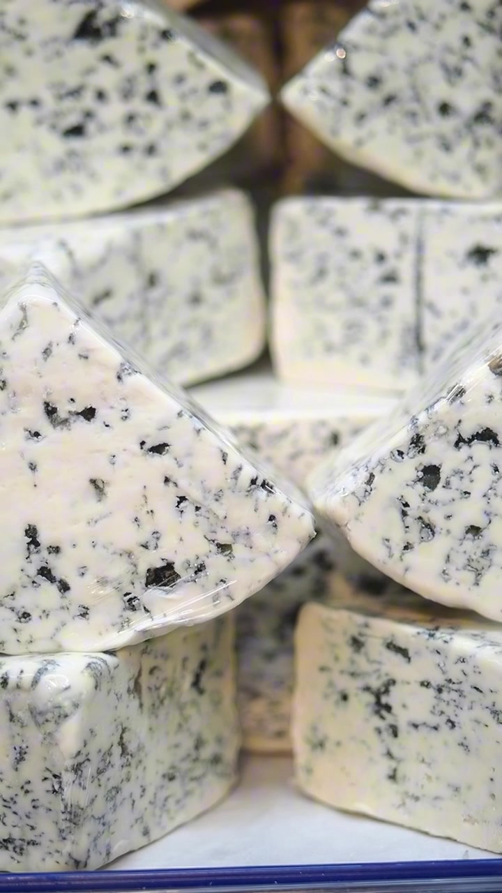 Spicchi freschi di formaggio erborinato esposti in un mercato
