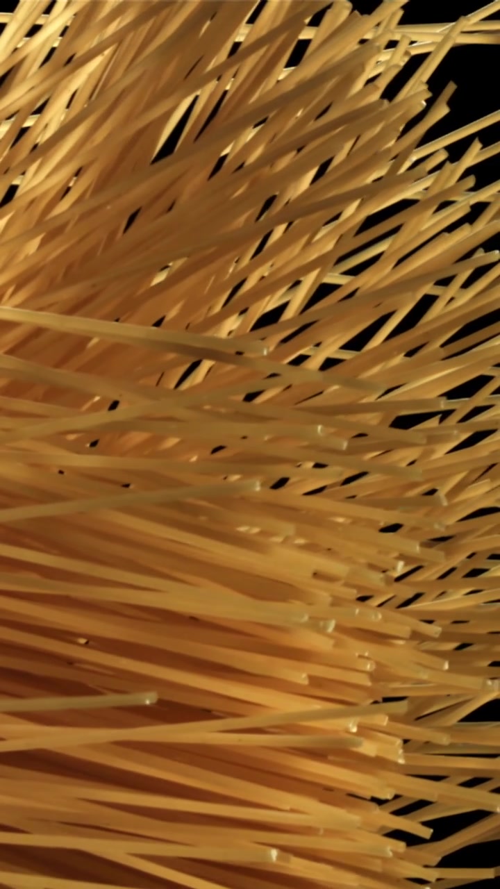 Spaghetti crudi dorati che si innalzano su sfondo nero