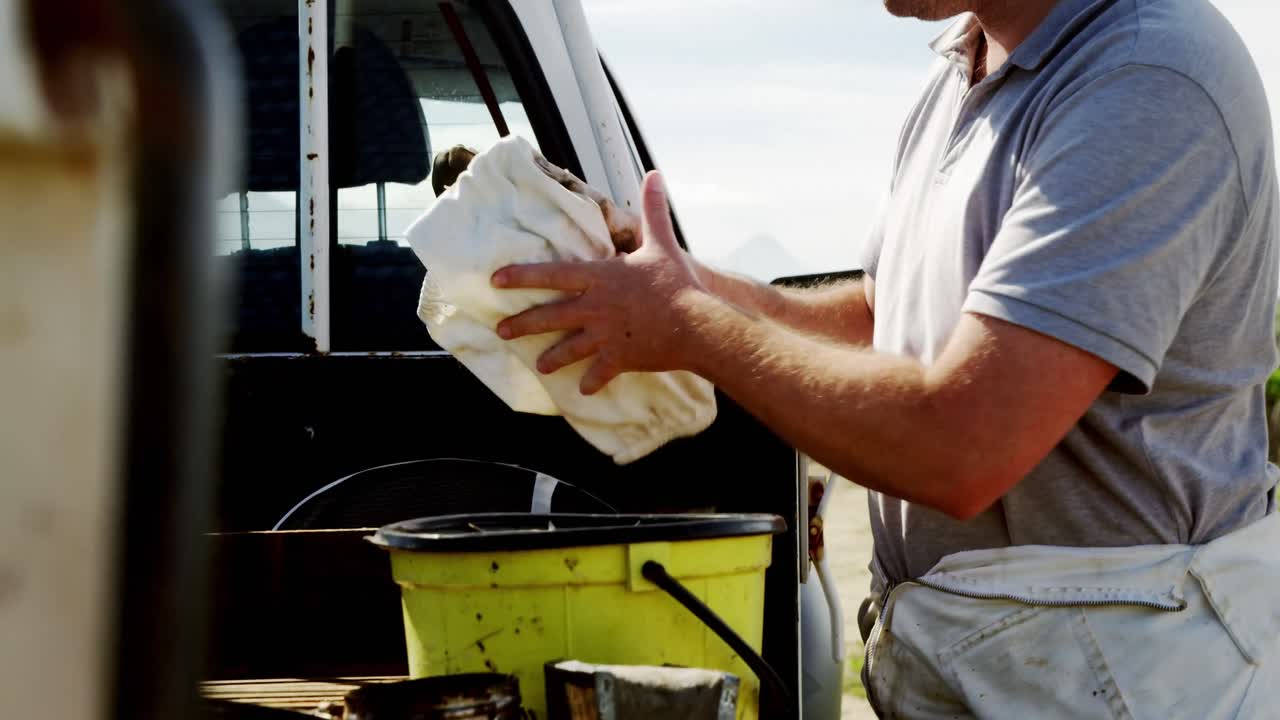 Apicoltore che ripone l'abbigliamento da lavoro in un contenitore sul camion