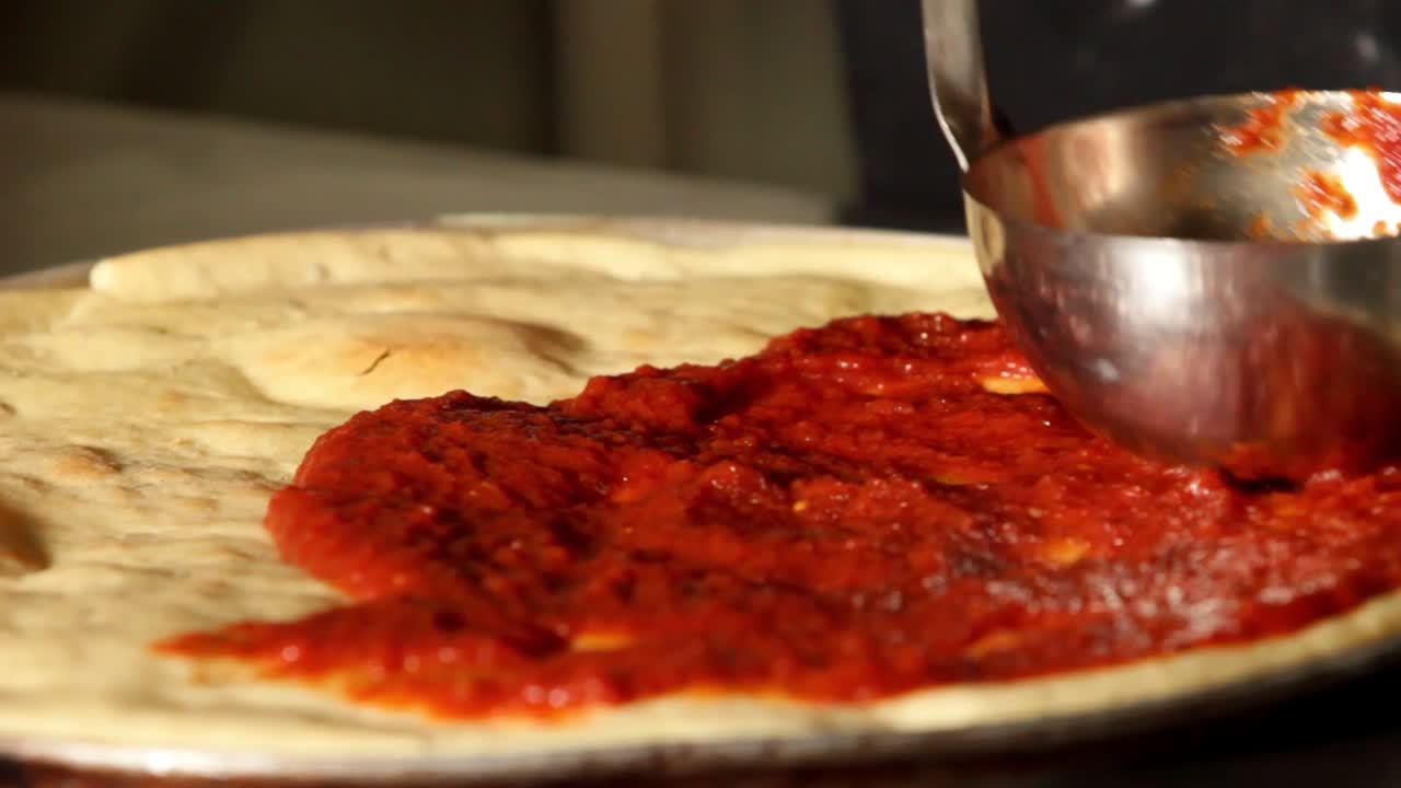 spreading delicious red tomato sauce on a pizza