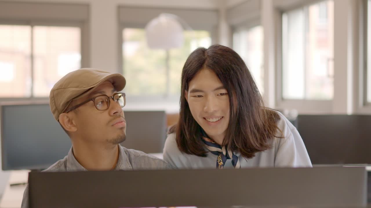 Multi-ethnic coworkers using computer and talking in the office