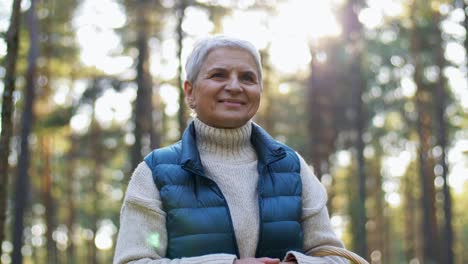 smiling senior woman hiking in autumn forest