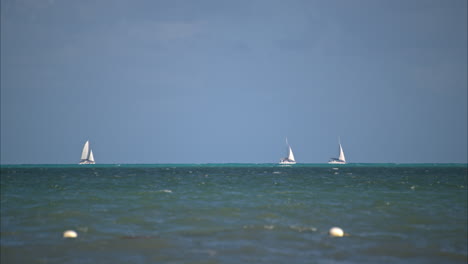 three boats sailing on the horizon at the caribbean sea on a sunny summer day