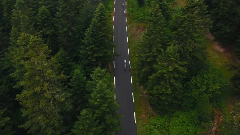 Grupo-De-Ciclistas-En-Un-Recorrido-En-Bicicleta-Por-Los-Pirineos-Franceses-Vista-Aérea-De-Drones-Escalando-Una-Montaña-Rodeada-De-árboles-Altos