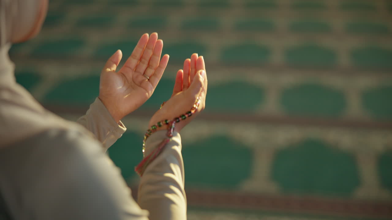 Muslim woman praying with rosary in mosque