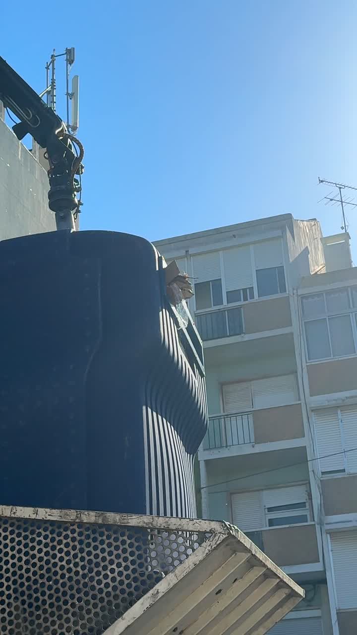 Gru che solleva un grande container accanto a un edificio urbano