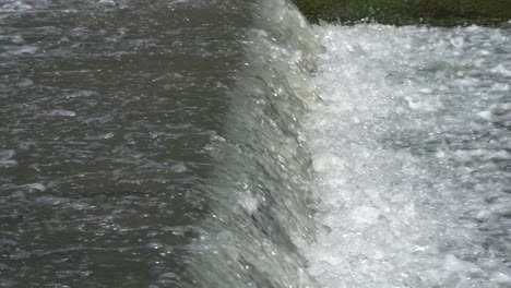 el agua salpicada fluye sobre una pequeña cascada artificial vista lateral de primer plano