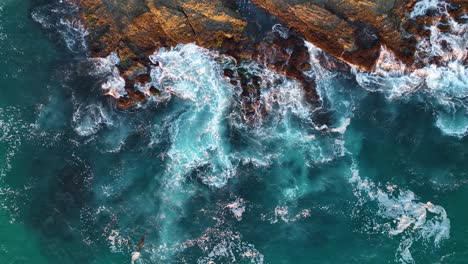 aerial view of waves crashing against sea rocks