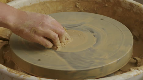 medium close up shot of cleaning a potter's wheel with a wet sponge