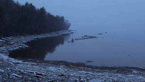 Beautiful,-lazy-slow-motion-snowfall-on-a-pristine-mountain-lake-during-a-nor'easter,-on-a-cold-moody,-atmospheric,-calm,-blue-evening