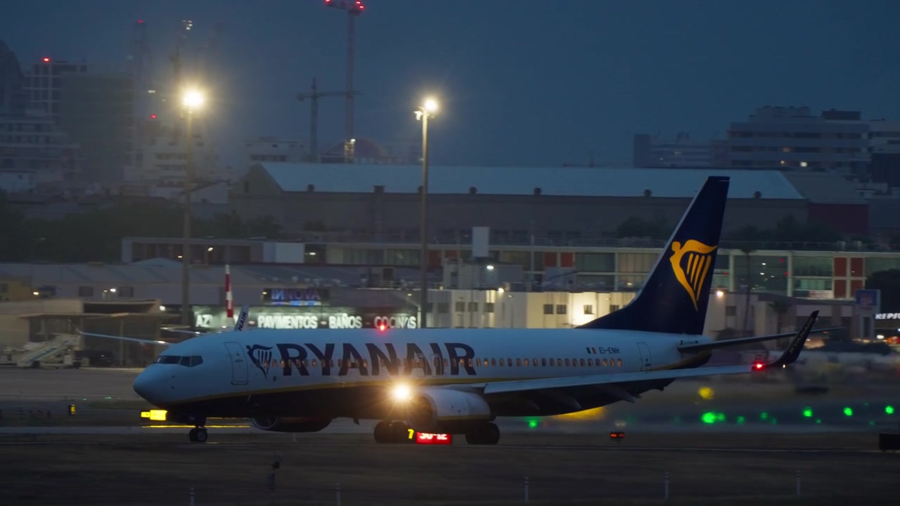 夜間の空港滑走路をタキシングするライアンエアーの旅客機