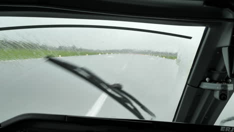 wiper of an airplane clearing the windshield from rain water upon landing on the airport runway on a bad weather - pov shot