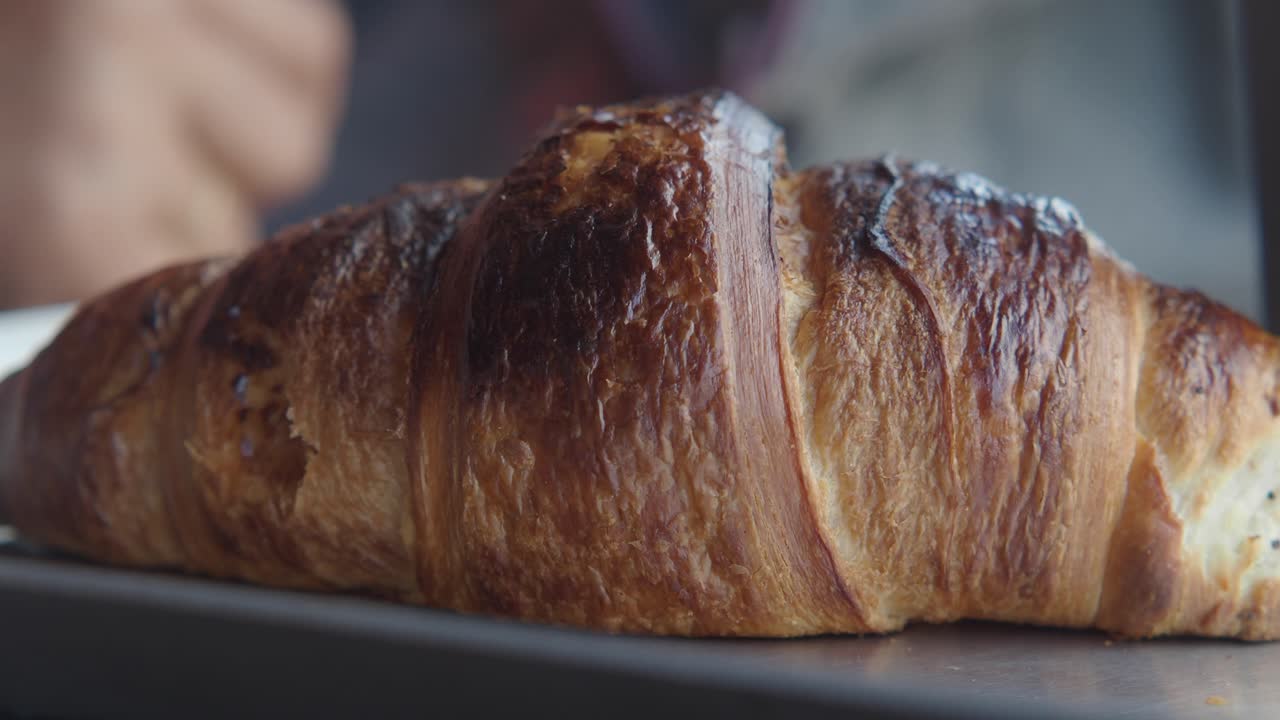 Primo piano di un croissant appena sfornato che viene preso